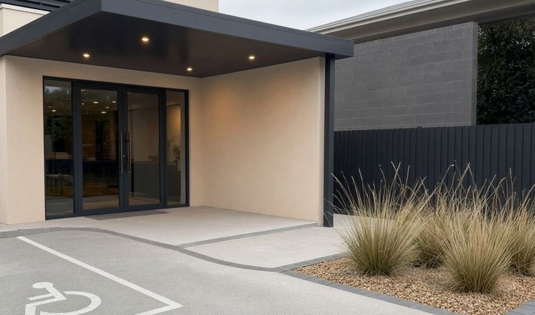 Covered hotel entry, glass doors and concrete driveway
